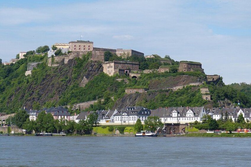 A historic castle on a hill overlooking a town with houses and a river. 3