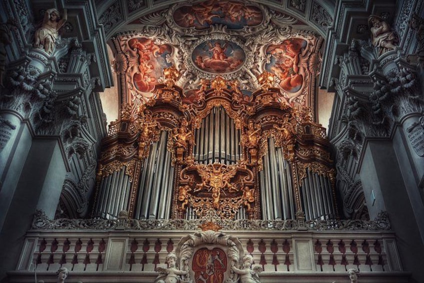 An ornate organ with intricate carvings and a detailed ceiling fresco. 3