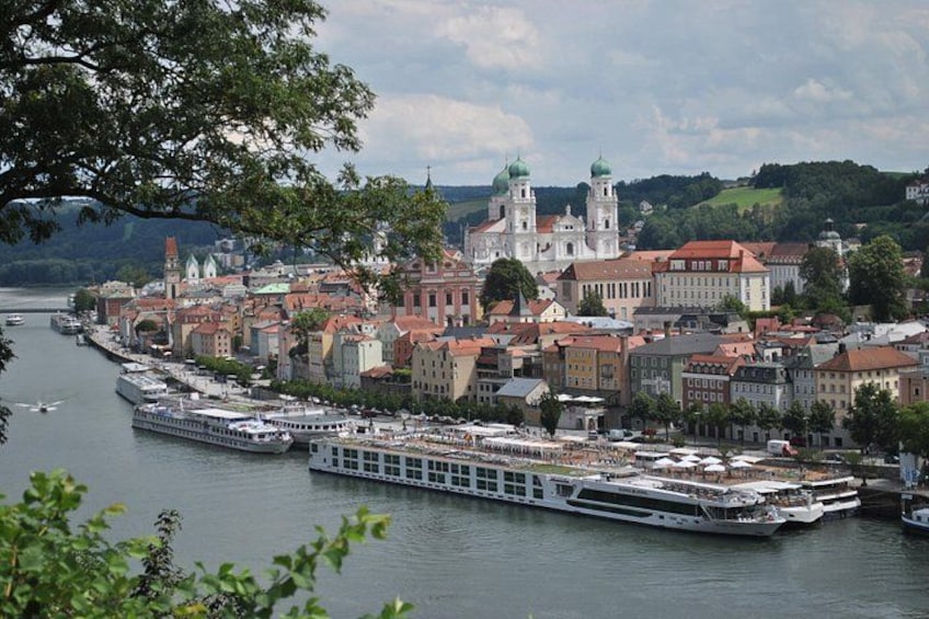 A river with boats, a cityscape with historic buildings, and a prominent church with two green domes. 1