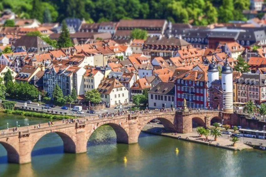 Ein Fluss mit einer Steinbrücke, bunten Gebäuden und einem Turm. 1
