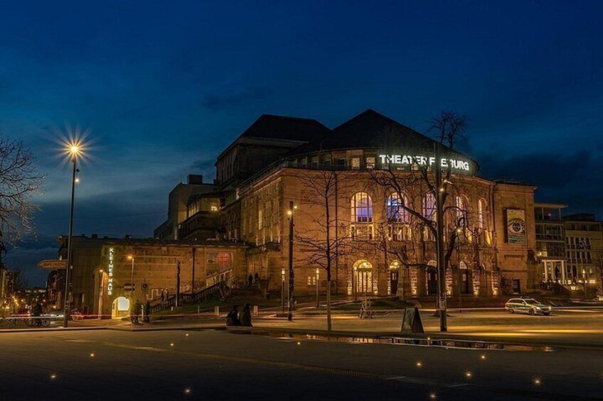A historic theater building at night with illuminated signage. 3