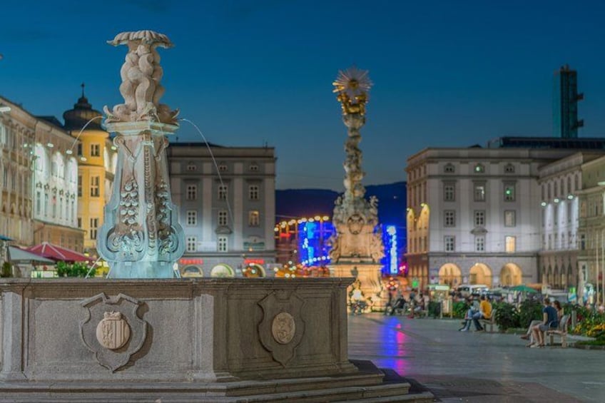 Une fontaine historique, ornée de sculptures raffinées, entourée d’une architecture classique et dont le fond est mis en valeur par des bâtiments illuminés. 2