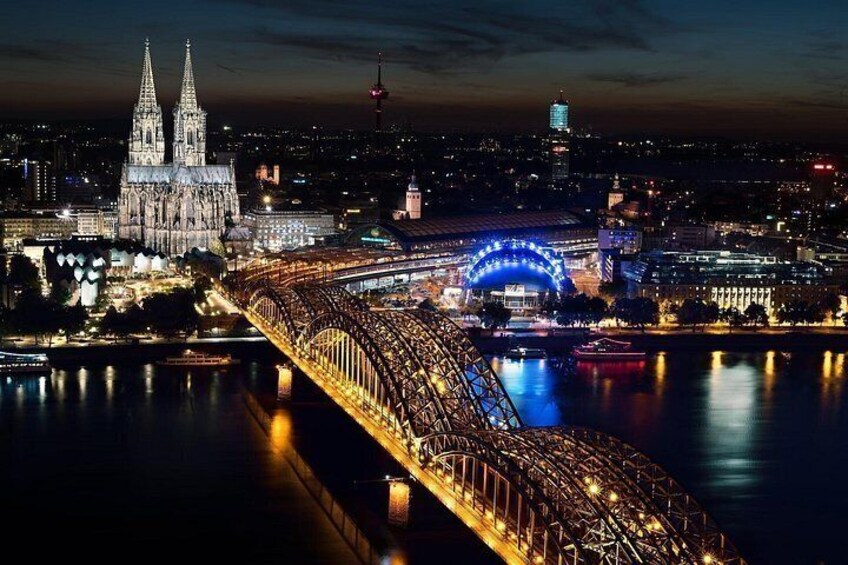 A nighttime cityscape with a prominent cathedral, a brightly lit bridge, and a blue-lit arch over a river. 2