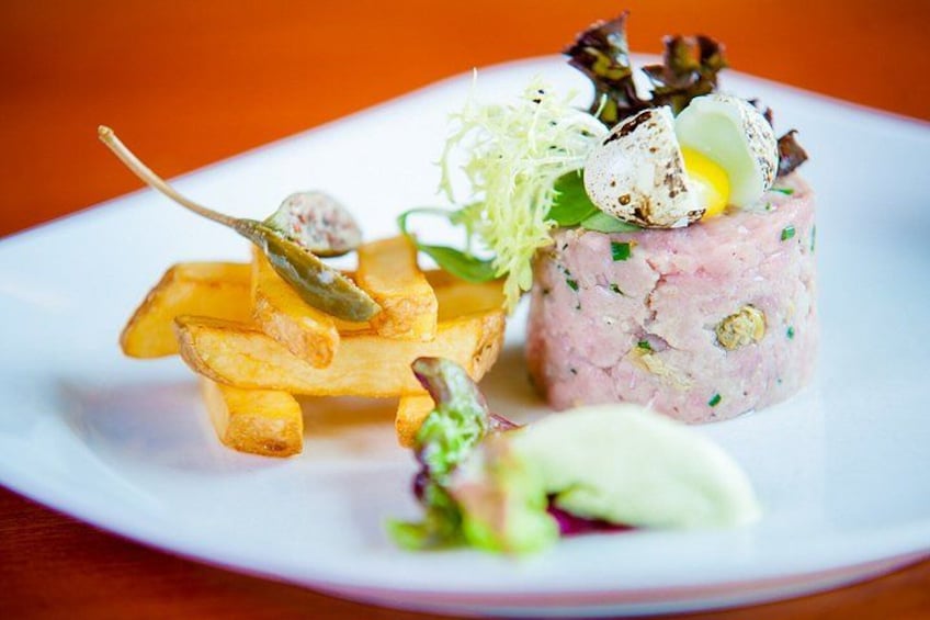 Een bord met een vleesgerecht, frieten en garneringen. 4