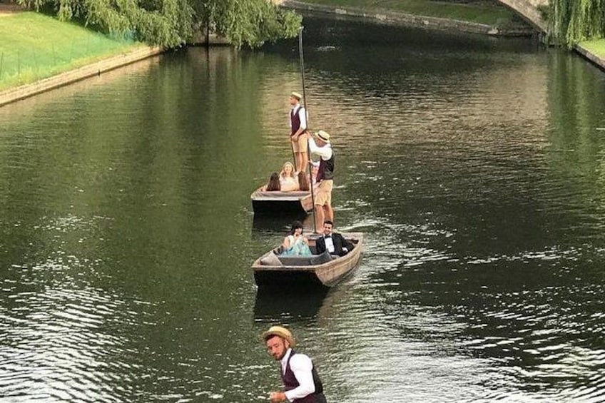En flod med to både, hvoraf den ene har folk stående og den anden en person, der ror. 2