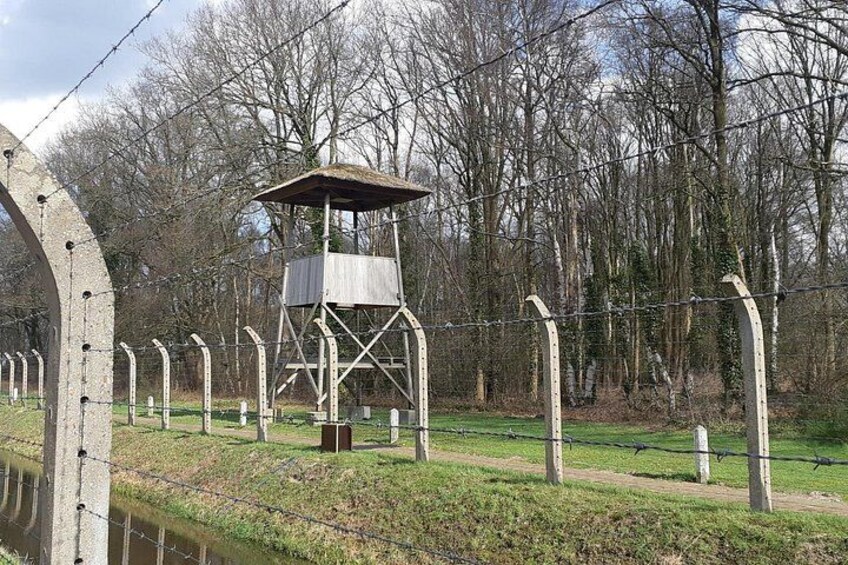 A watchtower, barbed wire fence, and a forested area. 3