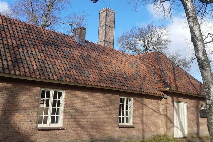 A brick building with a red-tiled roof, two windows, and a chimney. 2