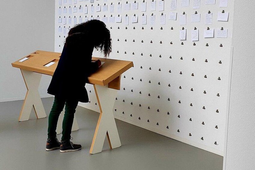 A child at a wooden table with papers pinned to a wall. 4