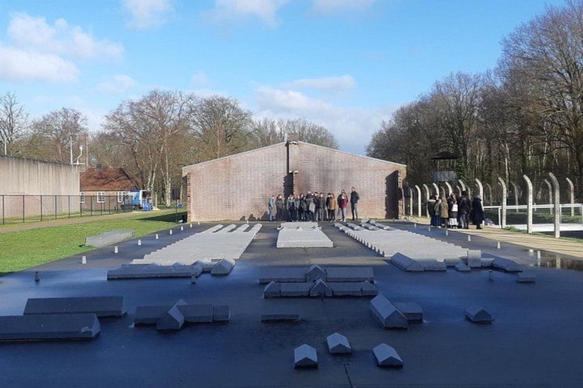 A memorial with a brick building, a paved pathway, and several white structures. 3