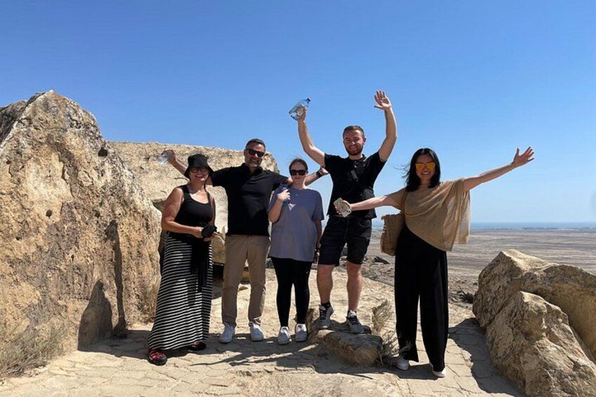 A group of people standing on rocky terrain with a clear sky in the background. 4