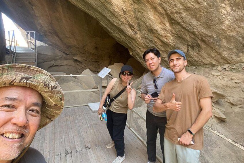 A group of people standing in a cave with a wooden walkway. 2