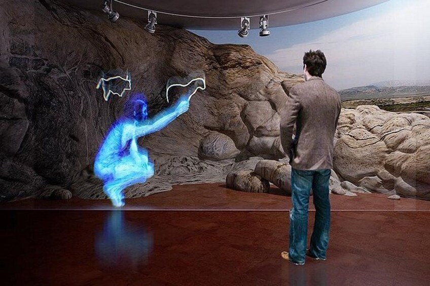 A man standing in a room with a rocky wall and a blue light effect. 5