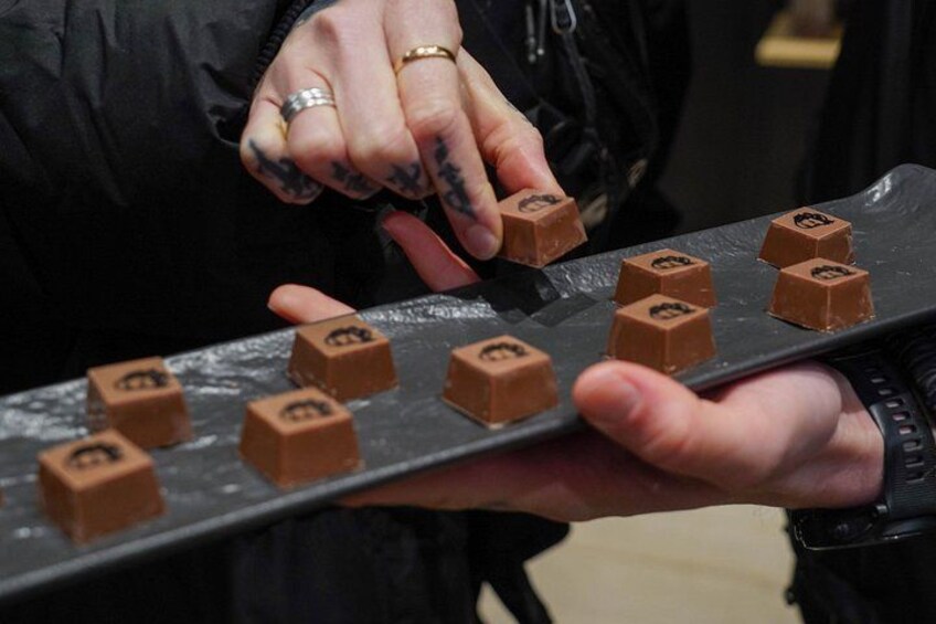 Una persona sostiene una bandeja con varios dulces cubiertos de chocolate. 2