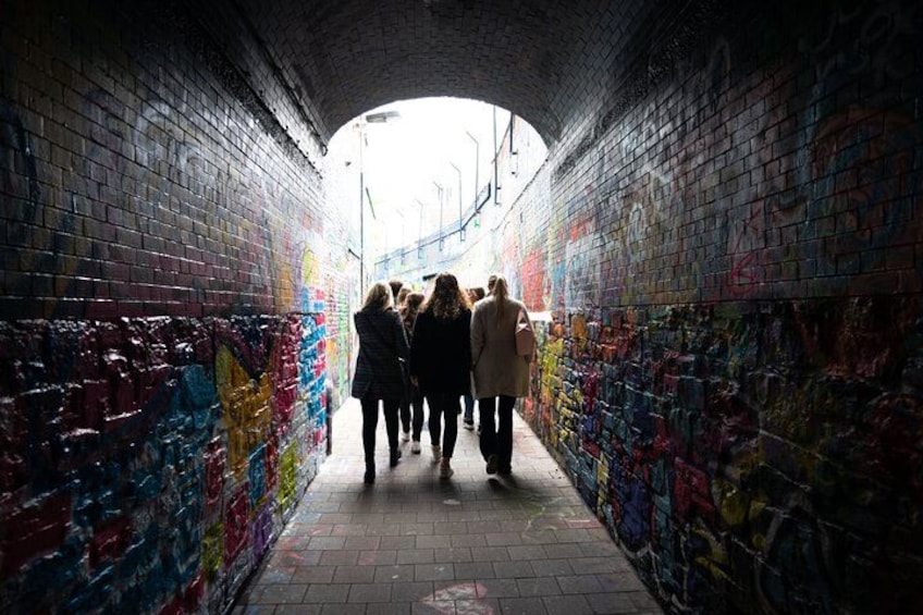 En tunnel med graffiti på væggene, hvor en gruppe mennesker går igennem. 4