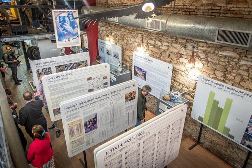 Una exhibición interior con paneles informativos y un fondo de pared de piedra. 1