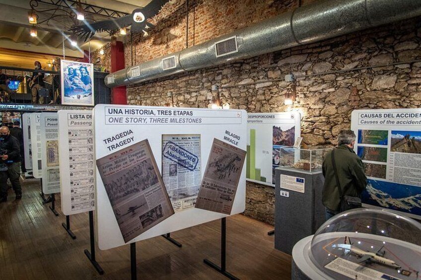An indoor exhibit with informational displays, a stone wall, and a model of an aircraft. 4