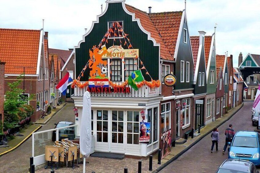 A street with traditional buildings, a sign for 'MOTJE' and 'AMSTERDAM', and a flag. 1