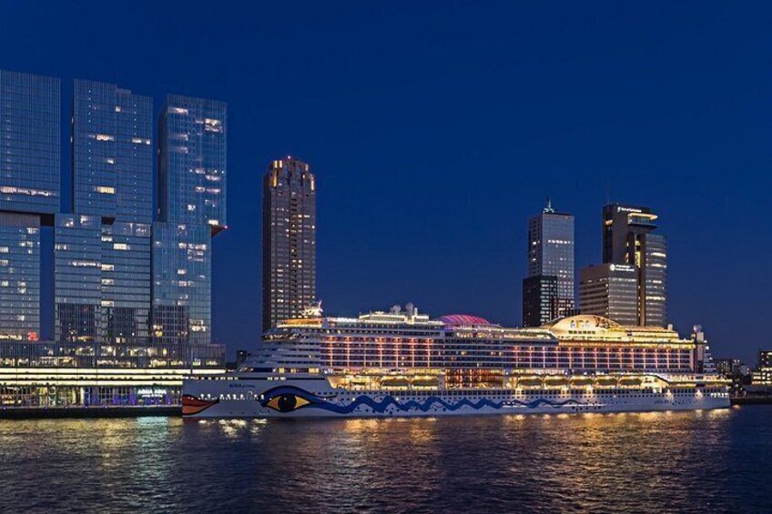 A cruise ship docked at a port with illuminated buildings in the background. 4