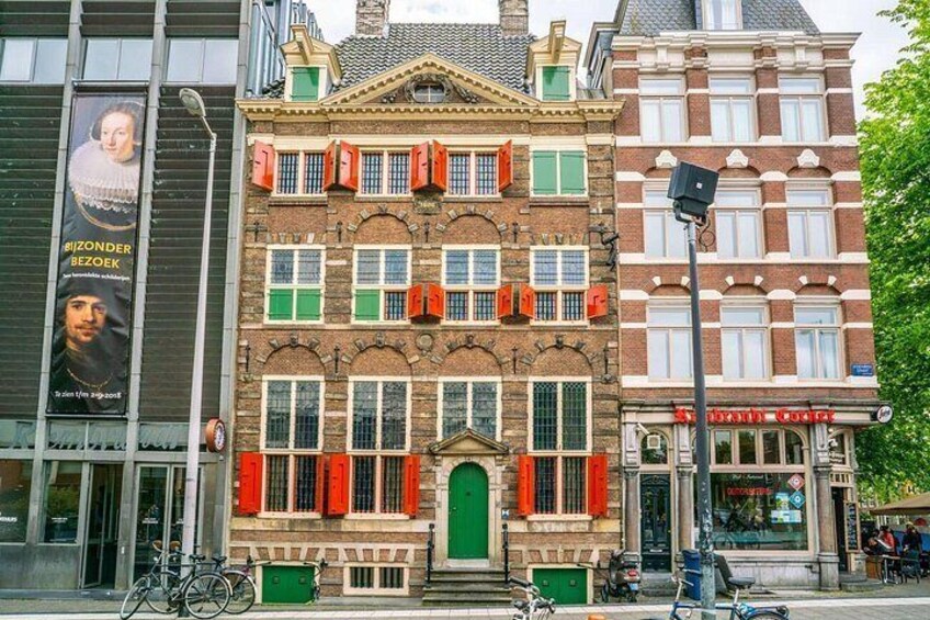 A historic building with red shutters, a green door, and a bicycle parked in front. 3