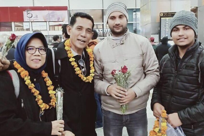 Four people standing together, holding flowers and wearing beanies. 3