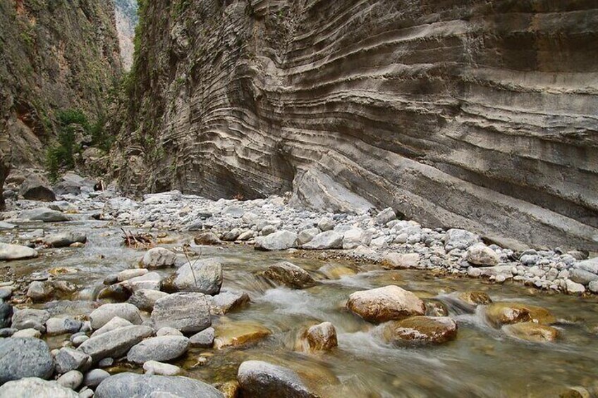 A river flowing through a canyon with layered rock formations and scattered boulders. 2