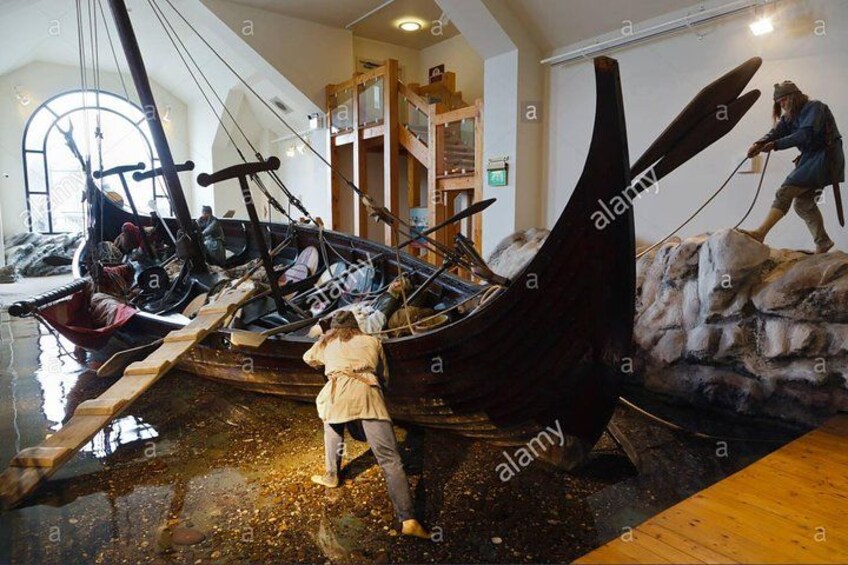 A museum exhibit with a Viking ship and a statue of a Viking. 2