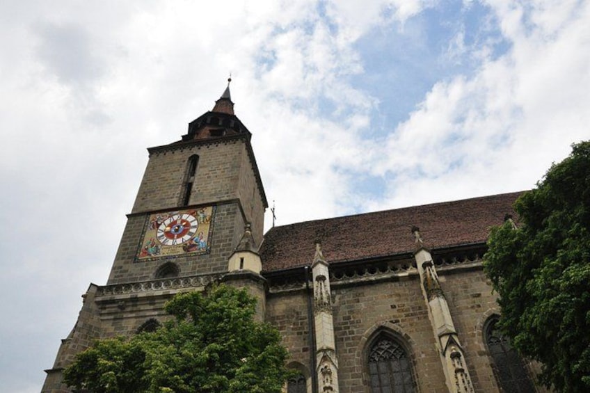 A historic church with a clock tower, intricate stonework, and a large stained glass window. 2