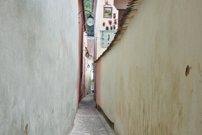 Une ruelle étroite bordée de bâtiments des deux côtés, avec un chemin pavé et du linge suspendu pour sécher. 3