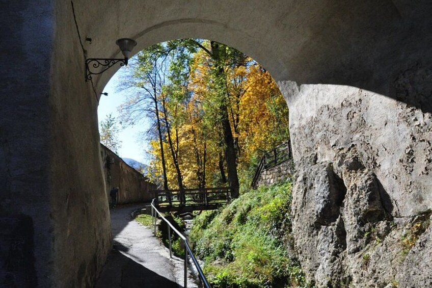 Un arco de piedra con vistas a árboles otoñales y un sendero. 2