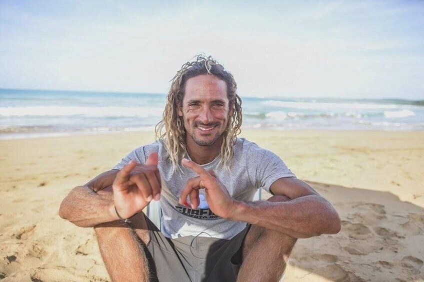 Une personne assise sur une plage, avec du sable et l’océan en arrière-plan. 4