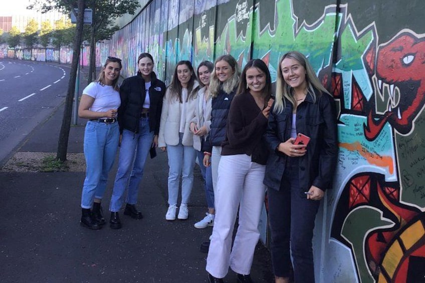 Een groep mensen staat voor een muur met kleurrijke graffiti. 2