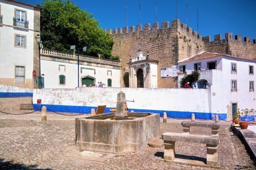 A historic fort with a stone wall, a fountain, and a cobblestone courtyard. 5