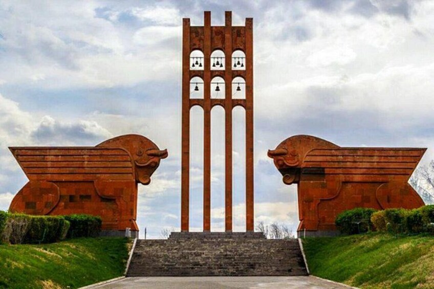 A monument with two lion statues and a tall structure with vertical elements. 1