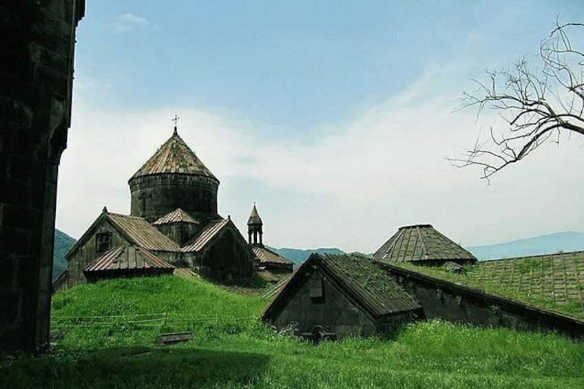 A rural church with a bell tower, surrounded by green fields and a clear sky. 1