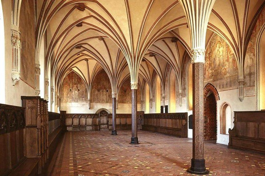 A cathedral interior with high vaulted ceilings, wooden pews, and a brick floor. 3