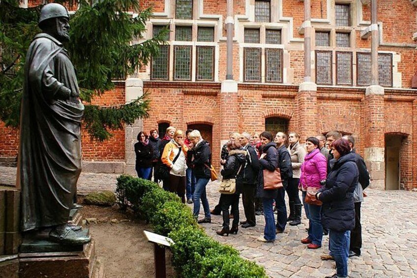 A group of people standing in a courtyard with a statue and a brick building in the background. 4