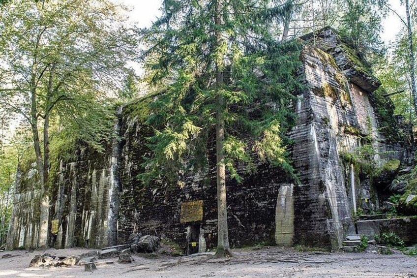 A forested area with a large rock formation and a sign. 3