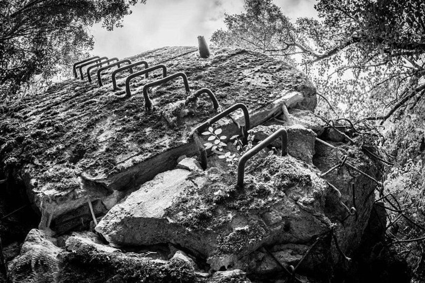 A rocky hillside with metal staircases and a person climbing. 4