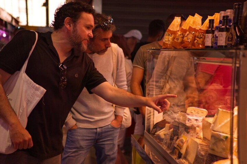 Dos personas observando objetos en un escaparate de vidrio en un mercado. 3