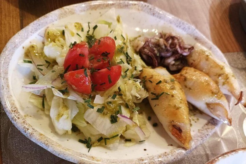 En tallrik med mat, bestående av en sallad, tomater och en bit grillad kyckling. 3