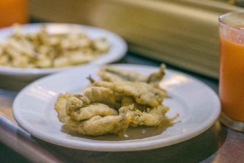 A plate of fried calamari with a glass of orange juice. 2