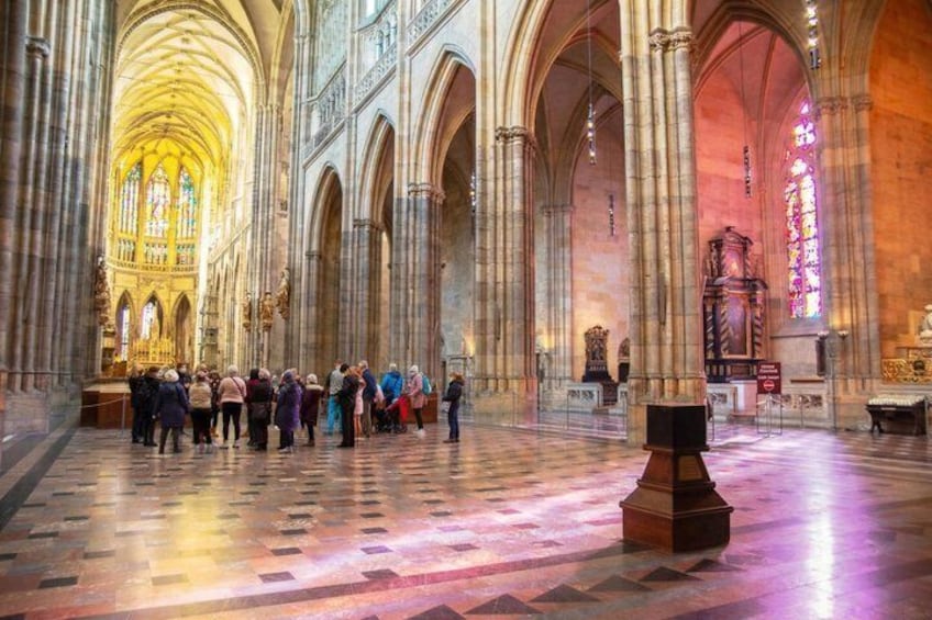 A cathedral interior with high vaulted ceilings and a group of people gathered in the nave. 4