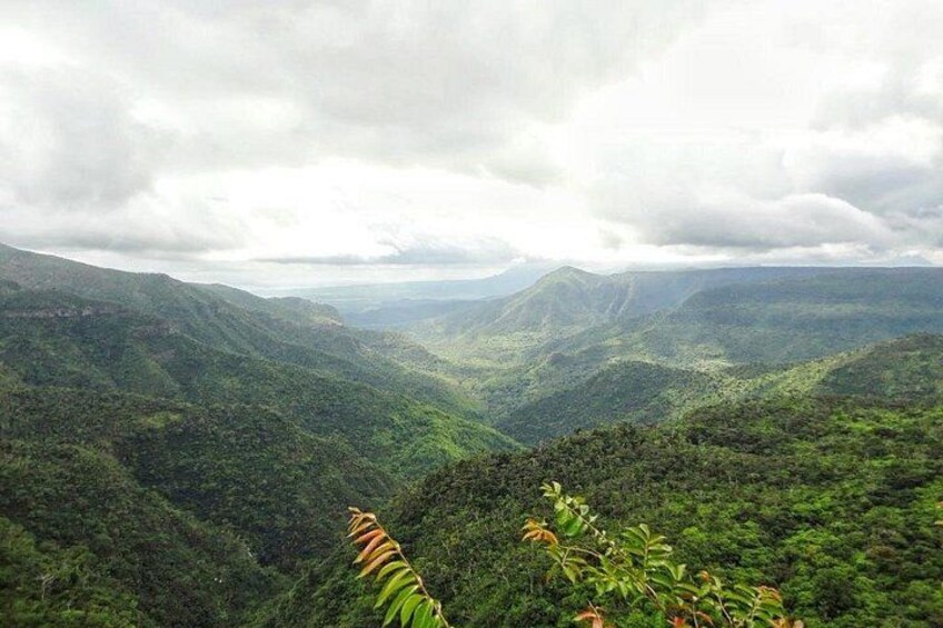 A mountainous landscape with dense green vegetation and a cloudy sky. 2