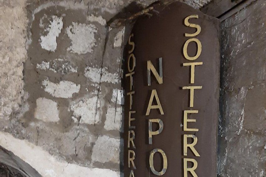A weathered stone wall with the inscription 'SOTTERNAPA' in gold lettering. 2