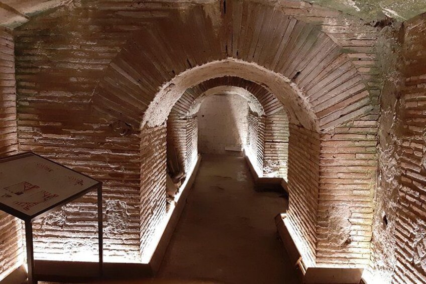 An arched brick tunnel with a sign on the left. 2