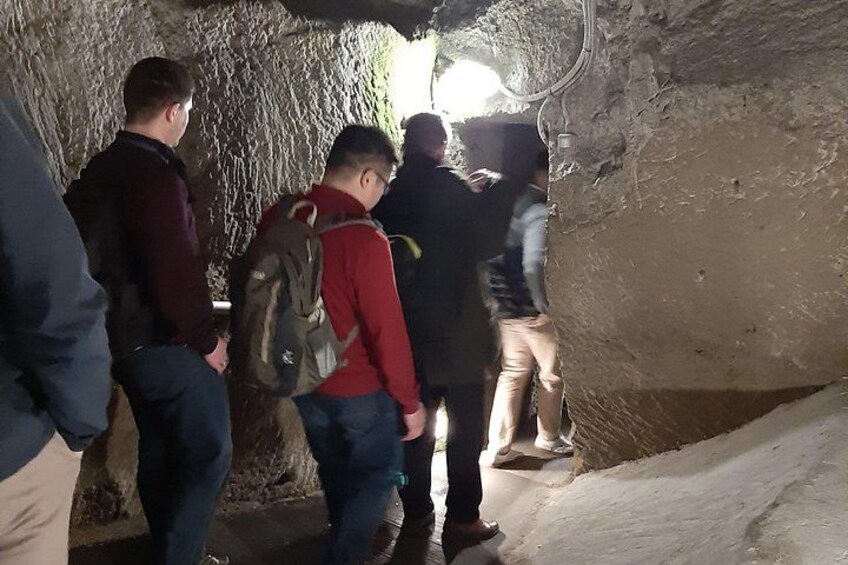 En gruppe mennesker udforsker en hule med ru vægge og en smal passage. 5