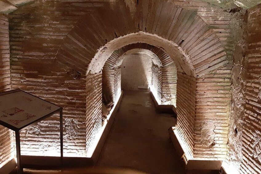 En murstens tunnel med hvælvede lofter og et skilt på venstre side. 3