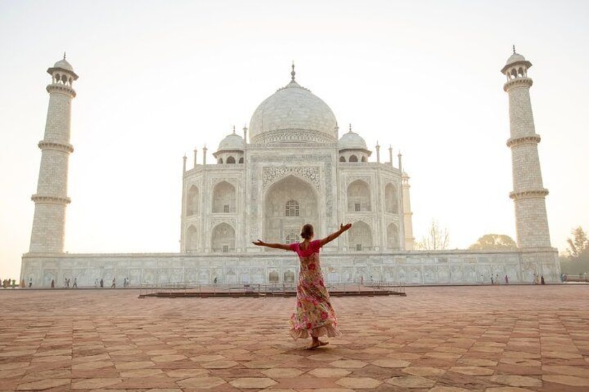 Een persoon in een rood en gouden jurk staat voor de Taj Mahal. 3