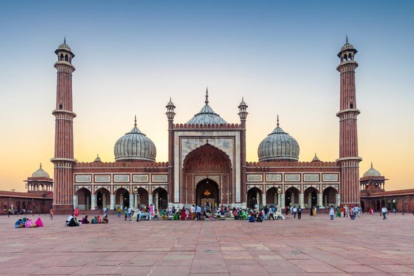 Una grande moschea con numerose cupole e minareti, un ampio cortile e persone riunite. 2