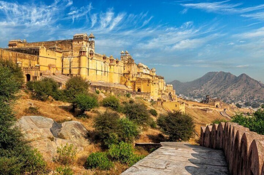 A historic fort with yellow walls, a stone pathway, and a mountainous backdrop. 3